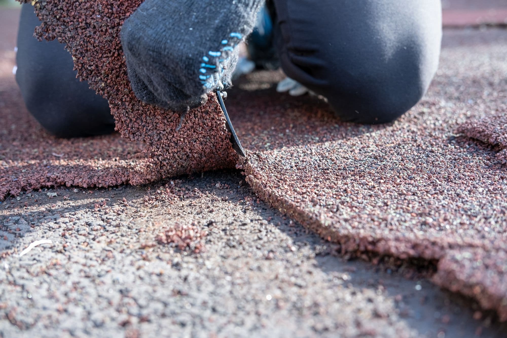 Close-up of hands installing asphalt shingles